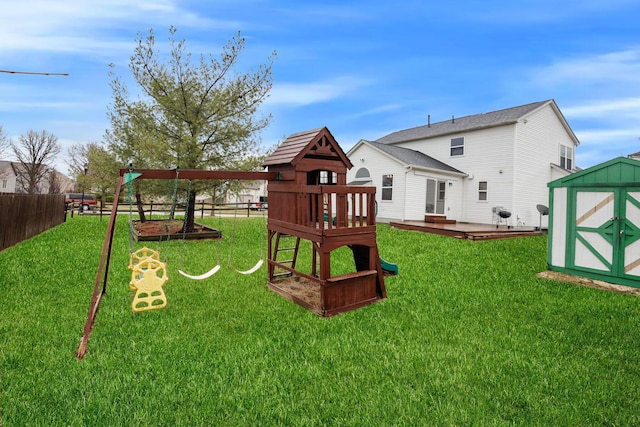 view of playground featuring a storage unit, an outbuilding, a lawn, and fence