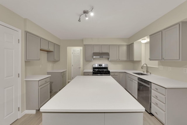 kitchen with a sink, appliances with stainless steel finishes, gray cabinets, and under cabinet range hood