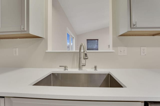 kitchen with a sink, vaulted ceiling, and light countertops