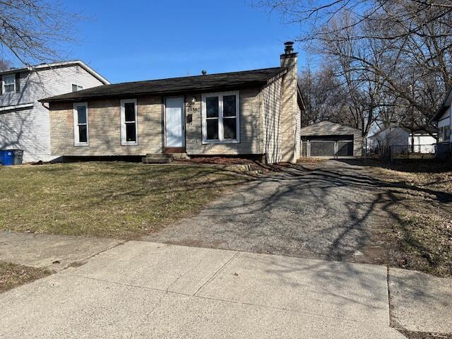 view of front of home featuring a chimney, a garage, a front yard, and an outdoor structure