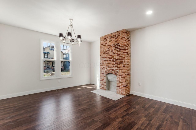 unfurnished living room featuring a brick fireplace, a notable chandelier, baseboards, and dark wood-style flooring