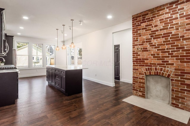 kitchen featuring dark wood-style floors, a center island, light countertops, and baseboards