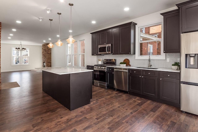 kitchen with a sink, light countertops, dark wood-type flooring, appliances with stainless steel finishes, and tasteful backsplash