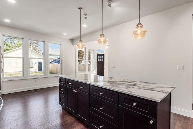 kitchen featuring dark wood-type flooring, light stone counters, baseboards, and pendant lighting