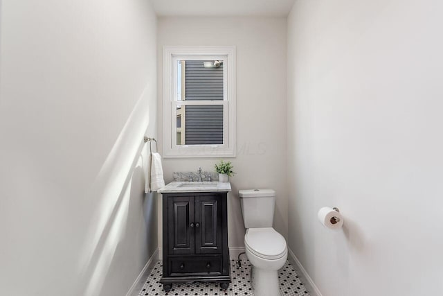 bathroom with toilet, vanity, and baseboards