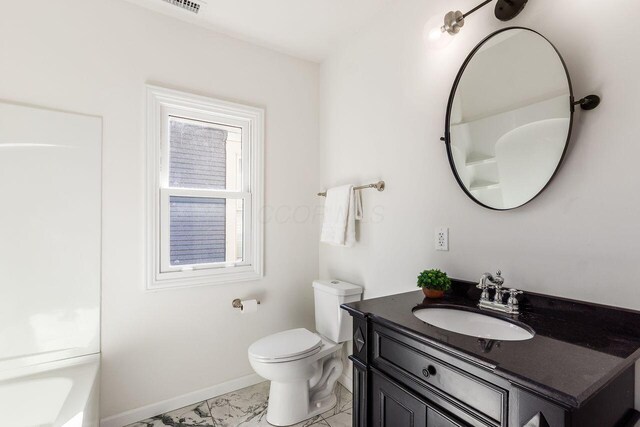 bathroom with toilet, marble finish floor, baseboards, a bathtub, and vanity