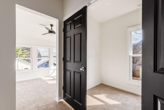 corridor featuring plenty of natural light, carpet, visible vents, and baseboards