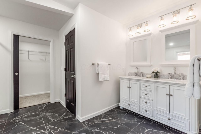 bathroom featuring double vanity, baseboards, marble finish floor, and a sink