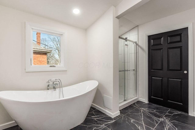 bathroom with baseboards, a freestanding bath, marble finish floor, and a shower stall