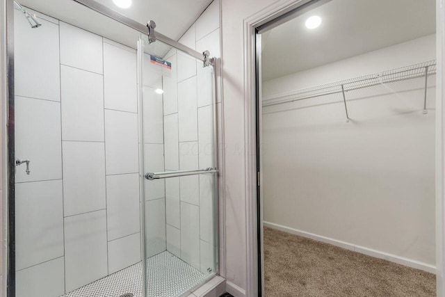 bathroom featuring a walk in closet, baseboards, and a shower stall