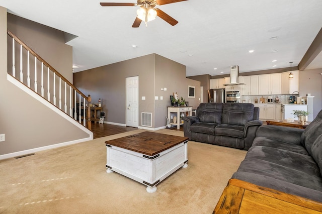 living area with stairway, light colored carpet, visible vents, and baseboards