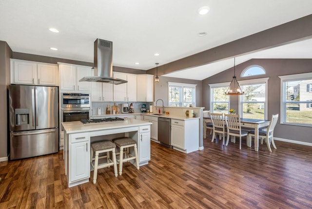 kitchen featuring island exhaust hood, a sink, appliances with stainless steel finishes, a peninsula, and light countertops