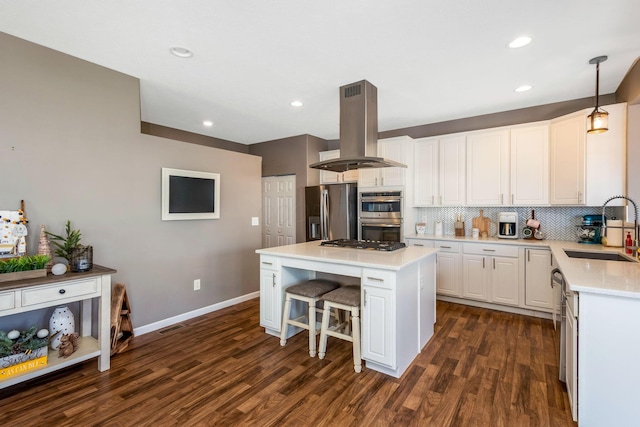 kitchen with a sink, dark wood finished floors, appliances with stainless steel finishes, island range hood, and decorative backsplash