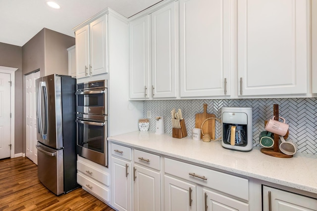 kitchen featuring decorative backsplash, white cabinets, wood finished floors, and stainless steel appliances