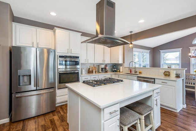 kitchen with lofted ceiling, appliances with stainless steel finishes, island exhaust hood, a peninsula, and a sink