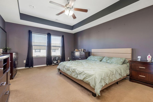 bedroom with light colored carpet, a ceiling fan, a raised ceiling, and baseboards