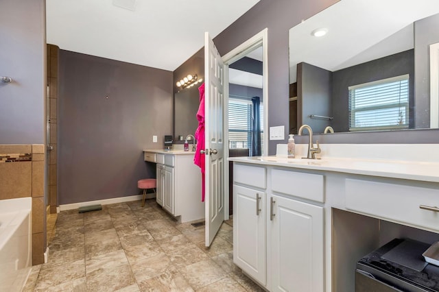 full bath featuring two vanities, plenty of natural light, and a sink