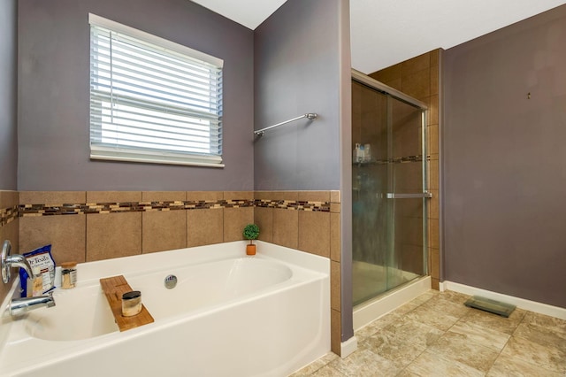 full bathroom featuring a bath, a shower stall, and baseboards