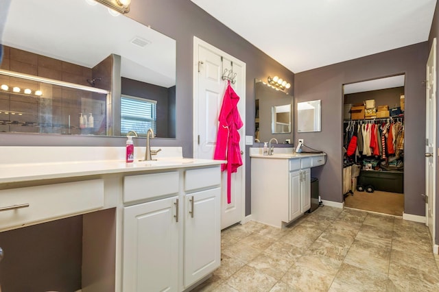 full bathroom with vanity, baseboards, visible vents, a shower stall, and a walk in closet