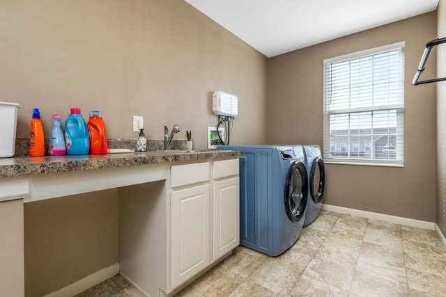 laundry area featuring cabinet space, baseboards, independent washer and dryer, and a sink