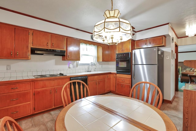2639 Halleck Dr, Columbus, OH 43209 - kitchen featuring under cabinet range hood, black appliances, tile counters, ornamental molding, and brown cabinets