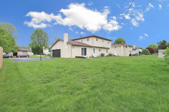 2639 Halleck Dr, Columbus, OH 43209 - back of house with asphalt driveway, a chimney, a garage, stucco siding, and a yard