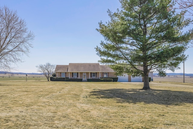 view of front facade featuring brick siding, a front yard, a rural view, and a garage