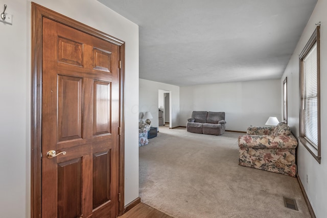 carpeted living area featuring baseboards and visible vents