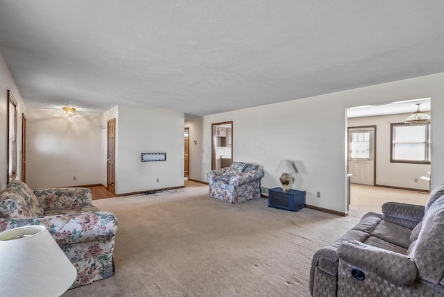 living room with light carpet, a textured ceiling, and baseboards