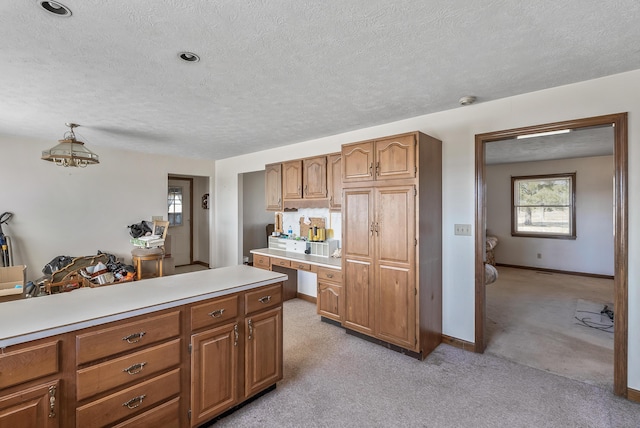 kitchen featuring light countertops, light colored carpet, and brown cabinets