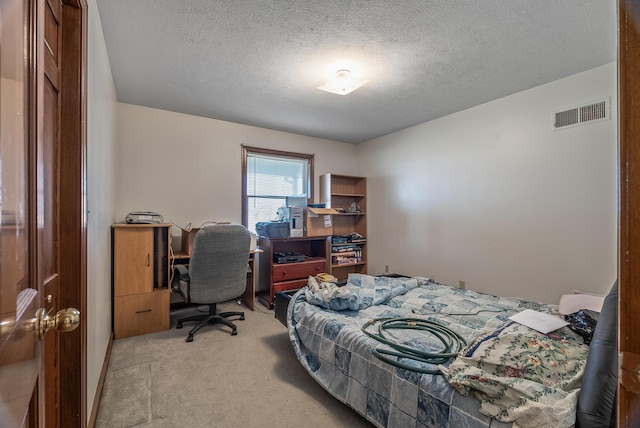 bedroom with visible vents, light colored carpet, and a textured ceiling