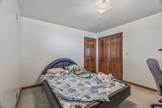 bedroom featuring a closet, baseboards, light colored carpet, and a textured ceiling