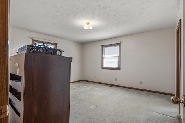 interior space with carpet flooring, visible vents, baseboards, and a textured ceiling