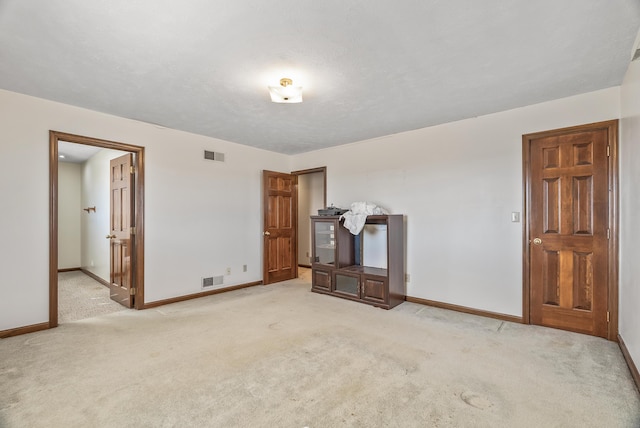 unfurnished living room with visible vents, baseboards, and carpet