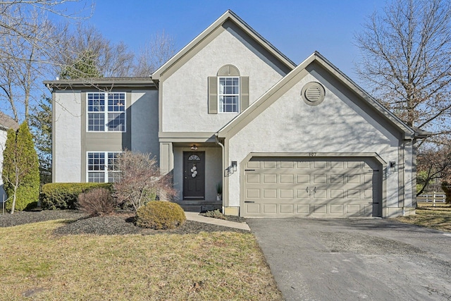 traditional home featuring aphalt driveway, a garage, a front yard, and stucco siding