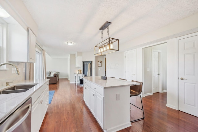 kitchen with a breakfast bar area, dark wood-style flooring, a sink, white cabinets, and dishwasher