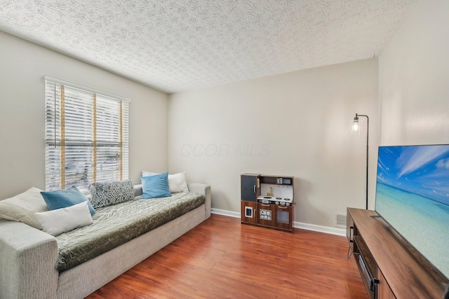 living area with wood finished floors, baseboards, and a textured ceiling