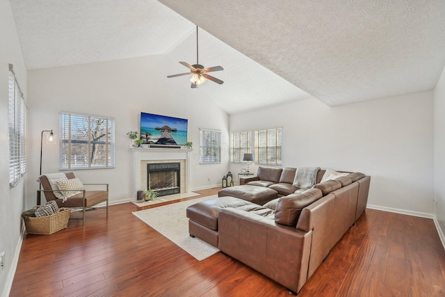 living room with dark wood finished floors, plenty of natural light, baseboards, and a tile fireplace