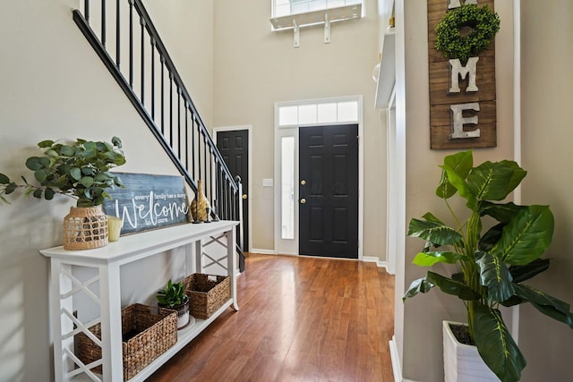 foyer entrance featuring stairs, a high ceiling, wood finished floors, and baseboards