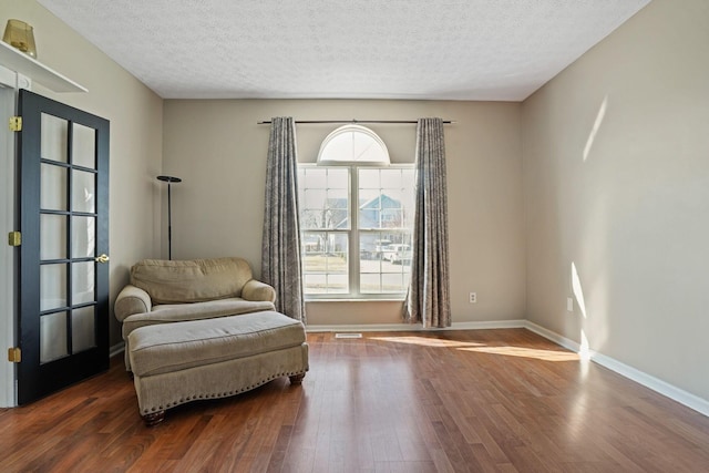 sitting room with wood finished floors, baseboards, and a textured ceiling