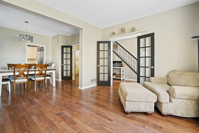 sitting room featuring baseboards, stairway, french doors, wood finished floors, and a textured ceiling