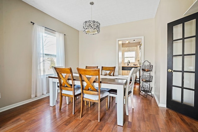 dining room featuring baseboards, plenty of natural light, and wood finished floors