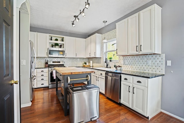 kitchen with open shelves, a sink, stainless steel appliances, white cabinetry, and butcher block counters