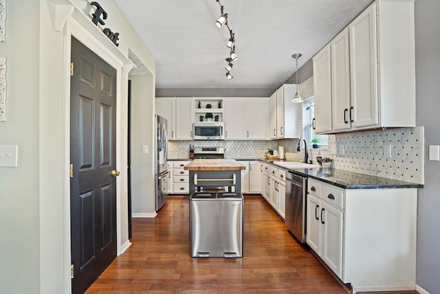 kitchen featuring open shelves, dark wood-style flooring, a sink, stainless steel appliances, and white cabinets