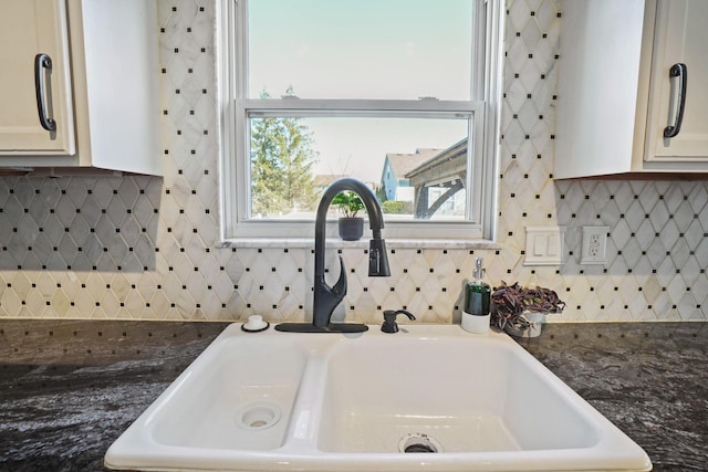 room details featuring a sink, backsplash, and dark countertops