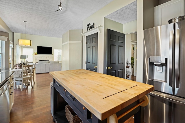 kitchen with wooden counters, dark wood finished floors, appliances with stainless steel finishes, a fireplace, and a textured ceiling