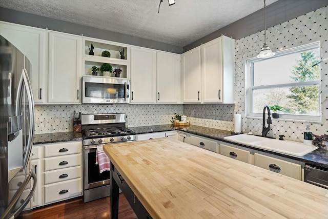 kitchen featuring butcher block countertops, a sink, white cabinetry, appliances with stainless steel finishes, and decorative backsplash