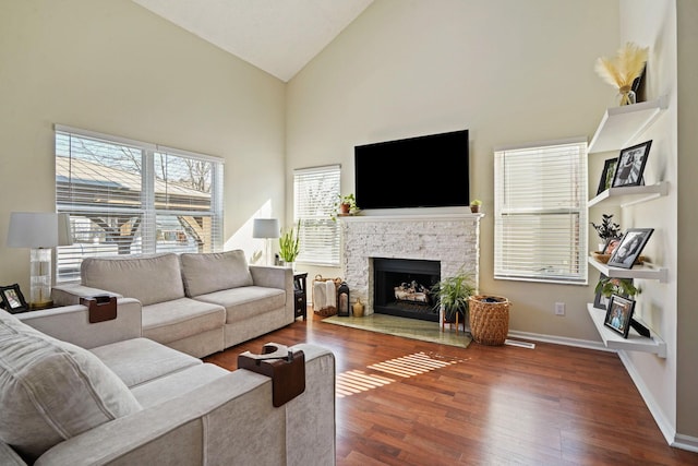 living area featuring a fireplace, wood finished floors, baseboards, and high vaulted ceiling