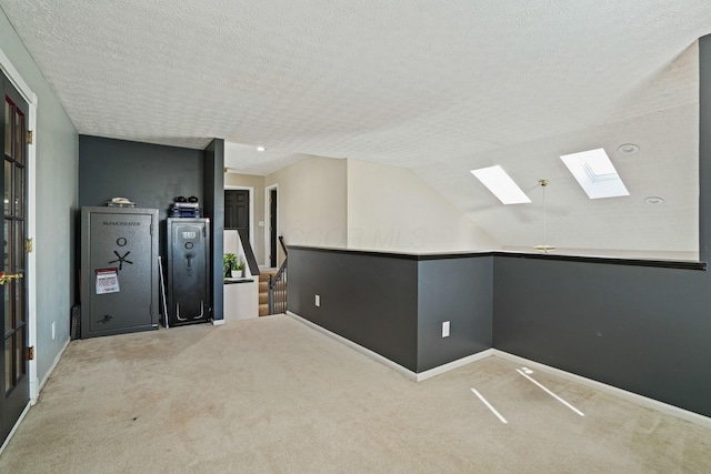 interior space with lofted ceiling with skylight, a textured ceiling, and baseboards