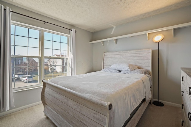 bedroom featuring light colored carpet, baseboards, and a textured ceiling